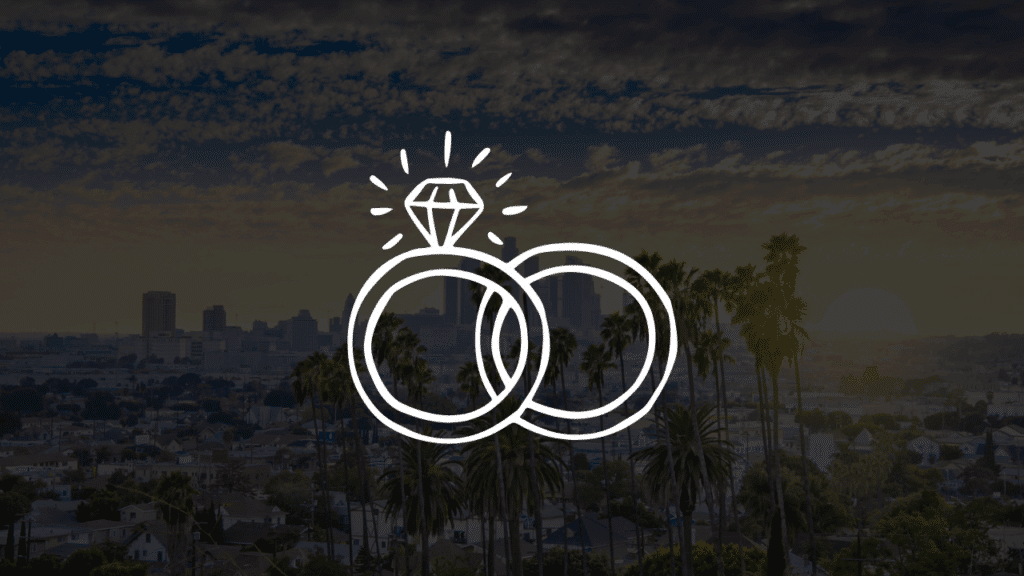 A white line art icon of intertwined wedding rings over a scenic sunset view of the Los Angeles skyline and palm trees, showcasing a beautiful Los Angeles wedding at Lucky Wedding Day Chapel.